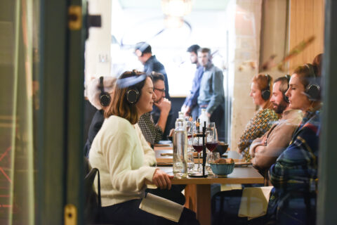 Personnes assises à une table de restaurant portant des casques audio