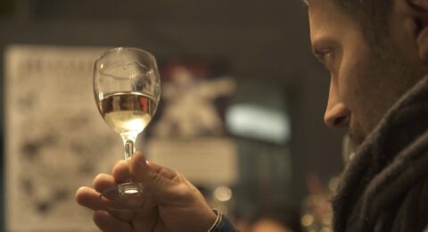 Homme examinant un verre de vin blanc lors d'une dégustation.