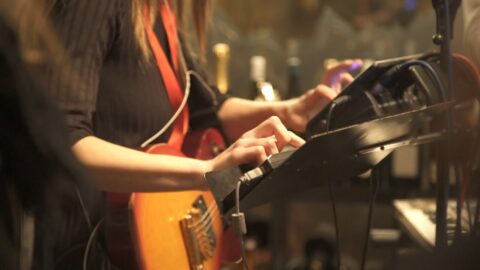 Musicienne jouant de la guitare et utilisant un appareil électronique lors d'un concert.