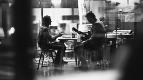 a black and white picture of two musician in a bar speaking about music