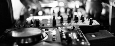 photo en plan serré de mains qui manipulent du matériel de DJ, en noir et blanc.